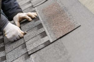 Homeowner reviews roof damage photos and insurance papers beside a window during winter weather.
